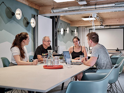Meetingraum mit Menschen die an einem Tisch zusammensitzen im Kreativpark Lokhalle | © Christoph Düpper Fotografie