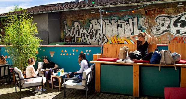 Sitzmöglichkeiten bei Sonnenschein inmitten von Pflanzen im Café POW Innenhof