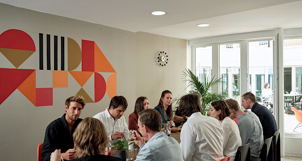 Coworkers having lunch together at a long table in the coworking kitchen at Grünhof Augustinerplatz