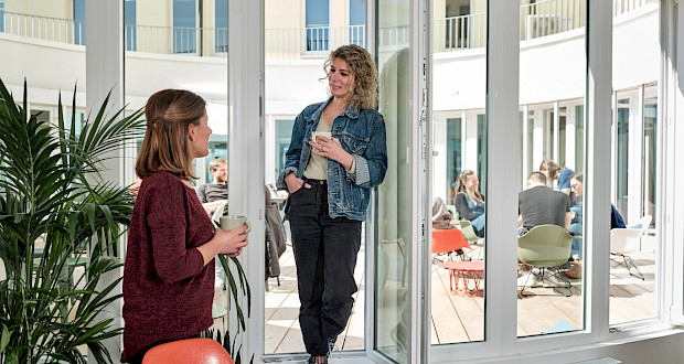Two people chat in the kitchen with access to the roof terrace at the Grünhof location Augustinerplatz