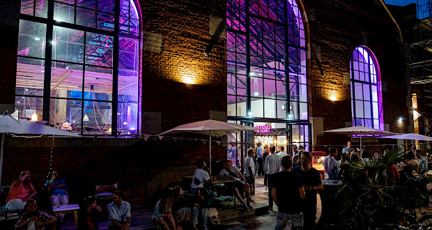 Community Sommerfest bei Nacht in beleuchteter Lokhalle